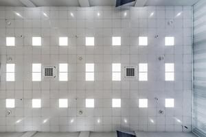 cassette stretched or suspended ceiling with square halogen spots lamps and drywall construction in empty room in house or office. Looking up view photo