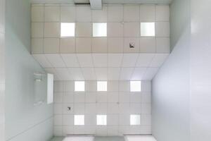 cassette stretched or suspended ceiling with square halogen spots lamps and drywall construction in empty room in house or office. Looking up view photo