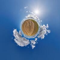 simple little tiny planet without buildings in blue sky with beautiful clouds. Transformation of spherical panorama 360 degrees. Spherical abstract aerial view. Curvature of space. photo