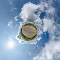 simple little tiny planet without buildings in blue sky with beautiful clouds. Transformation of spherical panorama 360 degrees. Spherical abstract aerial view. Curvature of space. photo