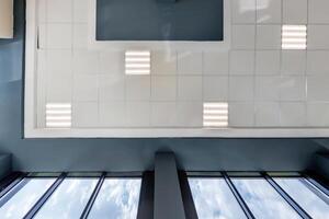 cassette stretched or suspended ceiling with square halogen spots lamps and drywall construction in empty room in house or office. Looking up view photo