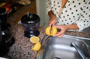 Woman in a polka dot shirt preparing fresh lemon juice in a modern kitchen setting photo