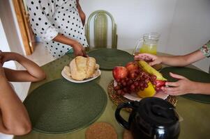 Family gathering around a table with fresh fruit, bread, and lemonade, creating a cozy and inviting atmosphere. photo