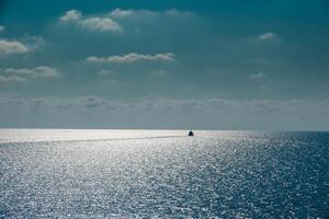 boat in the middle of the sea sails alone among the waves to the horizon on a late summer day in 2024 photo