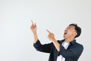 Excited Asian Indonesian man with Blue Shirt Pointing on Empty Space on Left Above photo