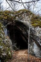 Entrance to a small cave, sandy floor in a karst sinkhole, natural object, Tourist route. photo