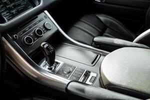 Close-up of the gearbox, the interior of an expensive car, the beautiful interior of the car, the black color of the instruments, the control buttons. photo