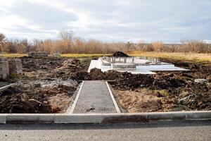 suburban construction, view of the construction of the house, concrete foundation, pillow of the foundation of the house, asphalt on the road, excavated earth. photo