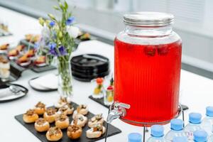 Catering in office, juice can, red lingonberry drink, sweet table, festive table setting, drink jug. photo