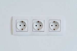Three sockets in the wall are shot close-up, the power output in the home room. photo