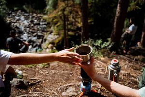 Pass each other a cup, hand pass a glass of tea to a friend, two hands, a hot drink, outdoor recreation, a cup of hot tea, hiking in the woods, camping in nature. photo
