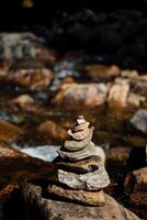 A pyramid of stones on the river, flat stones lie in a stack in the bed of a mountain river, a balance in nature, a tour, a slide of cobblestones. photo