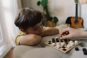 Teenage Girl and Boy Playing Board Game checkers In Living Room photo