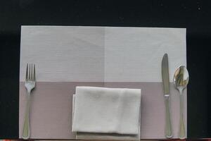 A silverware set is placed on a table with a napkin, set for a meal. photo