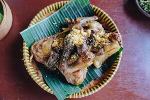 Traditional fried chicken with a yellow crispy condiment served on top of banana leaf. photo