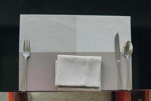 A silverware set is placed on a table with a napkin, set for a meal. photo