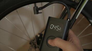 Man using cordless portable air pump inflating bicycle tire photo