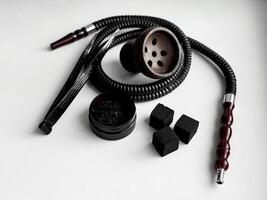 Traditional hookah set with hose, bowl, tongs, and charcoal on white background photo