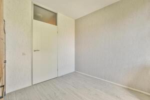 An empty room with a wooden door and white walls photo