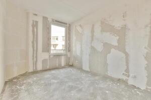 An empty room with a window and a wall covered in drywall photo