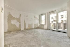 An empty room with a large window and a wall photo