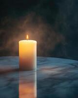 A pillar candle with a slow flame, casting light on a polished marble table photo