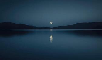 Bright full moon reflected in a still lake, distant hills barely visible in the darkness photo