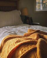 Knitted blanket in fall colors, soft and cozy, resting on the edge of a bed photo