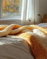 Knitted blanket in fall colors, soft and cozy, resting on the edge of a bed photo