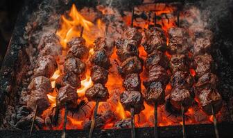 Skewers of lamb shashlik slowly turning over smoldering coals photo
