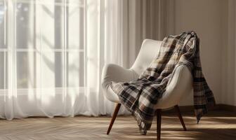 A white chair with a plaid blanket draped over it sits in front of a window photo