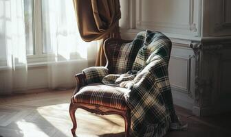 A chair with a blanket draped over it sits in a room with a window photo