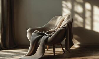 A chair with a blanket draped over it sits in a room with a window photo