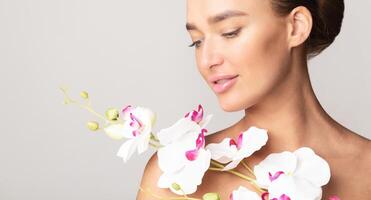 A woman holding a bouquet of white orchids in her hands, showcasing the delicate and elegant flowers on a neutral background, closeup, copy space photo