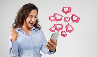 Happy young european woman with open mouth look at phone, celebrate success, win with fist raised up, have match on dating app, isolated on gray background. photo