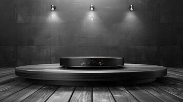 A black speaker sits on a wooden table in front of a wall photo