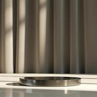 A round metal plate on a table in front of a curtain photo