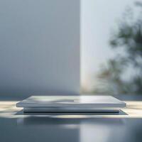 A white laptop sitting on a table in front of a window photo
