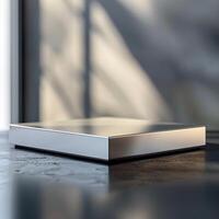 A silver box sitting on a table in front of a window photo