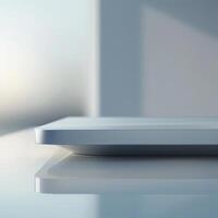 A white tablet sitting on a table with a window in the background photo