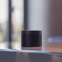 A black container sitting on a table in front of a window photo