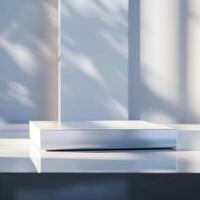 A white box sitting on a table in front of a window photo