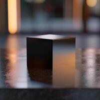 A black cube sitting on a table in front of a window photo
