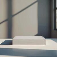 A white box sitting on a table in front of a window photo