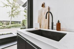 A kitchen sink with a black sink and white counter photo