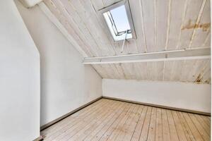 An empty attic with a skylight and wooden floor photo