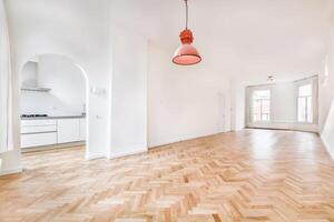 A large empty room with wooden floors and a red light hanging from the ceiling photo