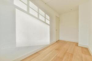A white room with a wooden floor and a window photo