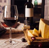 Glass of red wine with cheese and grapes on a table photo