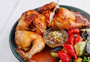 Roasted chicken with vegetables and sauce on rustic plate photo